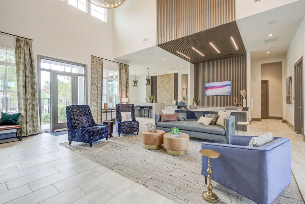 leasing office seating in mixed fabric chairs. Leasing desk has overhead lighting and flat screen TV.  other seating in the back at a high top table for meetings. Very tall and well lit ceilings.