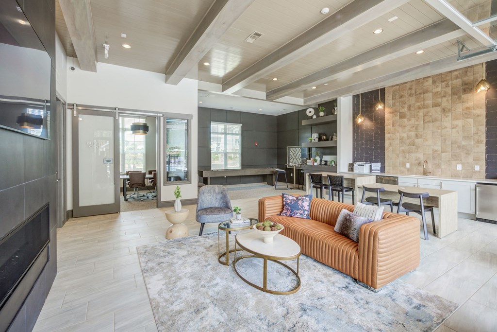 Resident lounge has wood beams in the ceiling, leather couch and chair in front of fireplace and flat screen TV.  Seating around a coffee bar with white granite counters.  Also, game area in the back with shuffle board and oversized checkers.