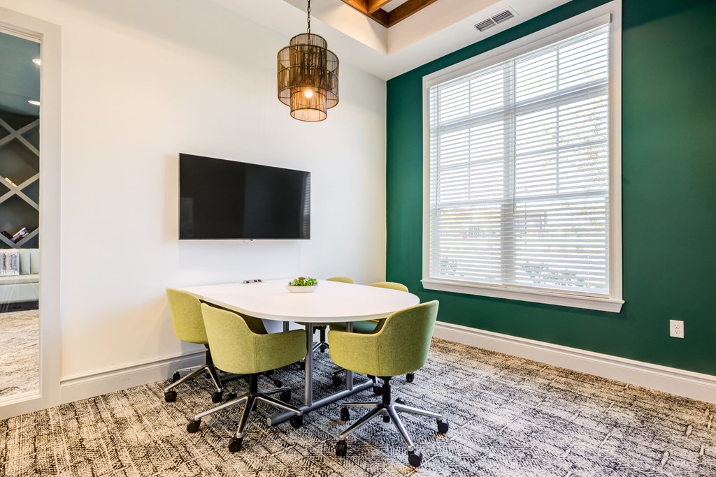 a meeting room with a table and chairs and a tv on the wall