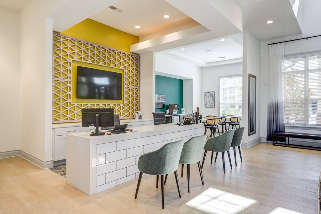 a room with a desk and chairs and a television on the wall