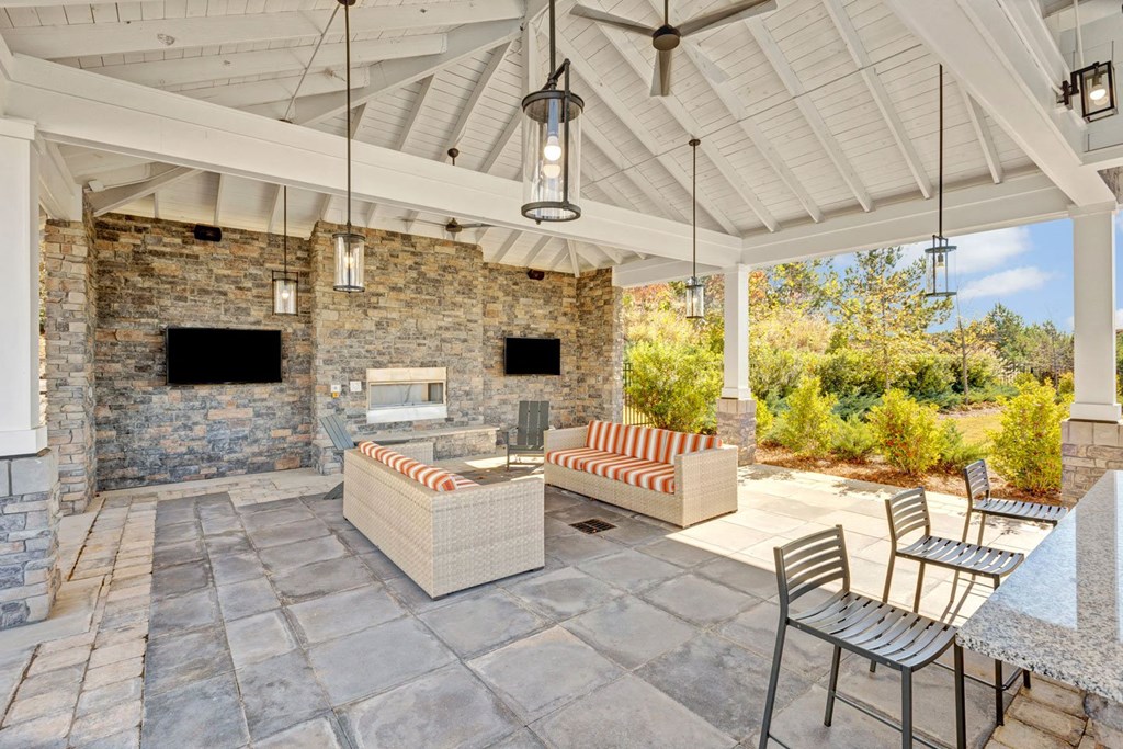 a covered patio with a stone fireplace and furniture