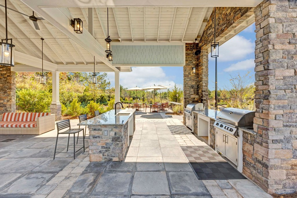 a large outdoor entertaining area with a grill and a table with chairs