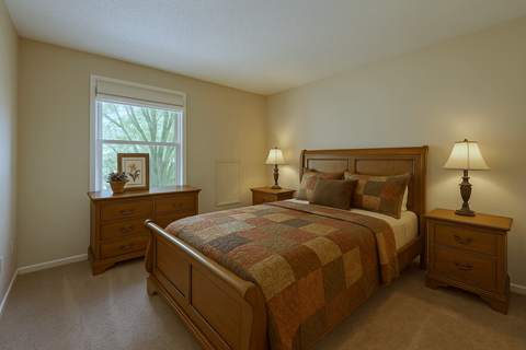 A bedroom with a bed, nightstands, and a window.