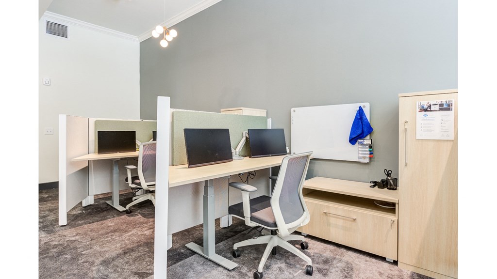 A room with two desks, one with a laptop and the other with a desktop computer.