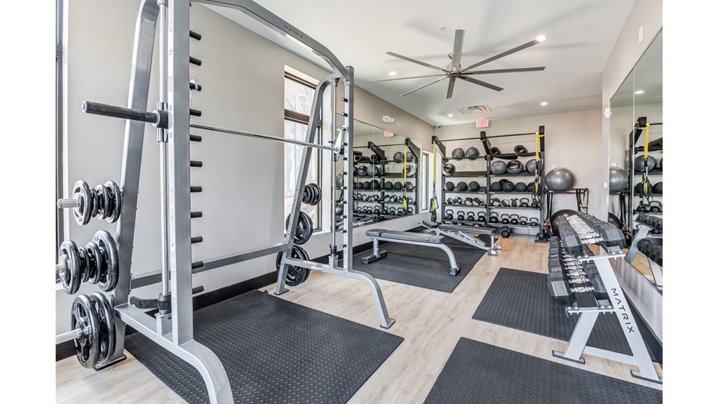 A gym with a variety of equipment including weights and benches.