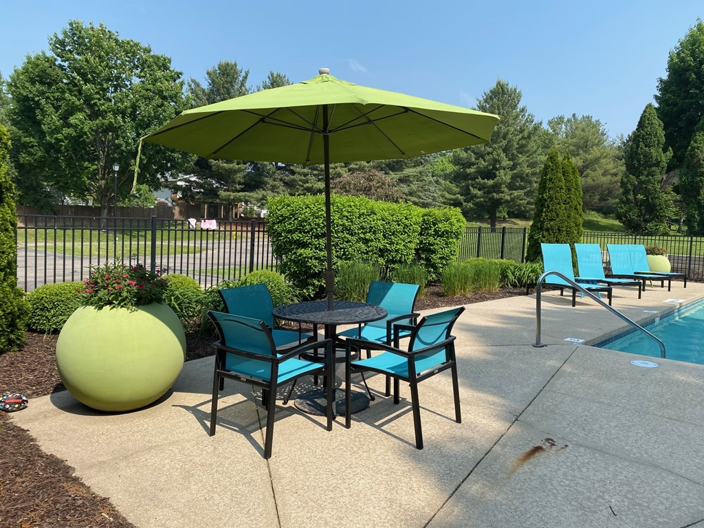 A green umbrella is above a table with chairs around it.