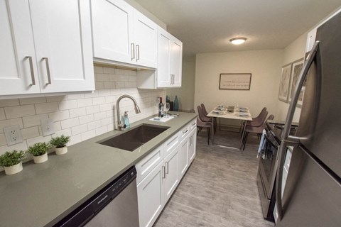 a kitchen and dining room with white cabinets and stainless steel appliances
