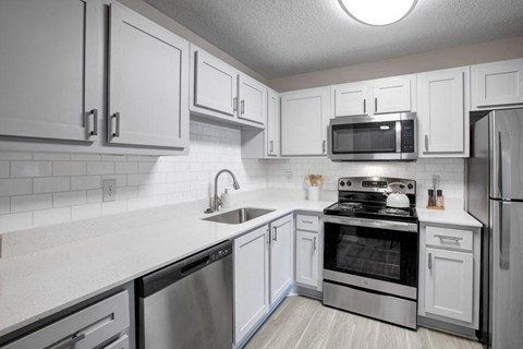 a white kitchen with stainless steel appliances and white cabinets