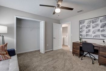 a bedroom with a desk and a ceiling fan