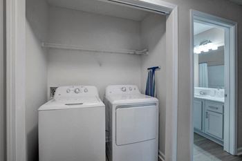 a white laundry room with two washes and a dryer