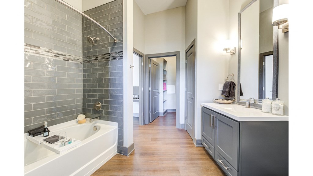 A bathroom with a white sink and a grey tiled wall.