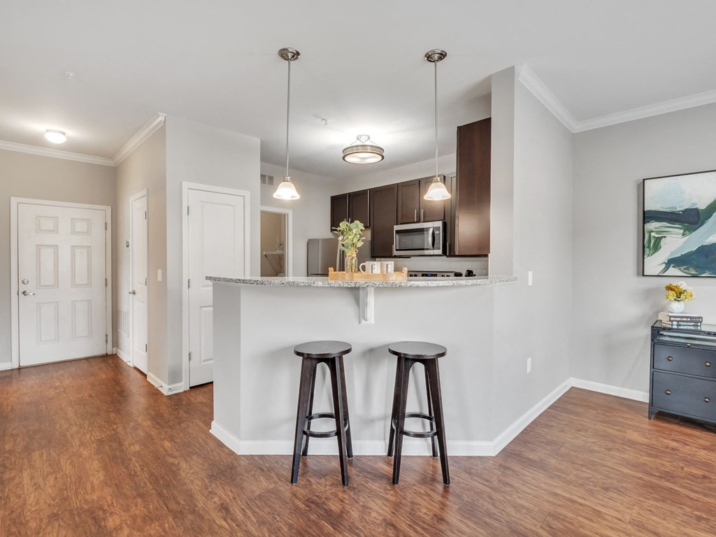 a kitchen with a bar and two stools in front of a kitchen counter