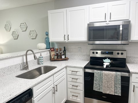 a kitchen with white cabinets and a sink and a microwave
