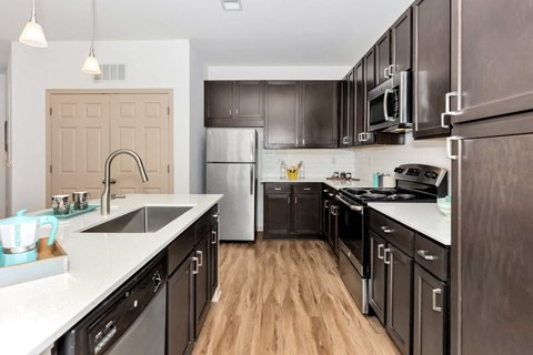 a large kitchen with black cabinets and stainless steel appliances