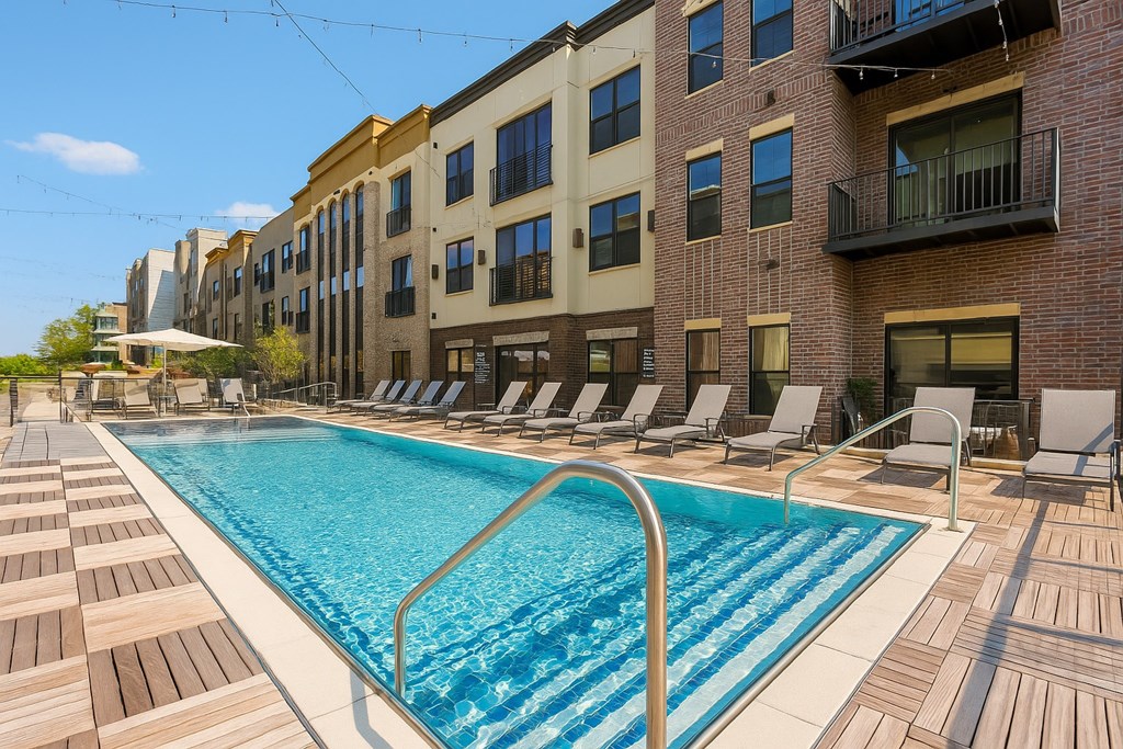 A pool surrounded by lounge chairs in front of a building.