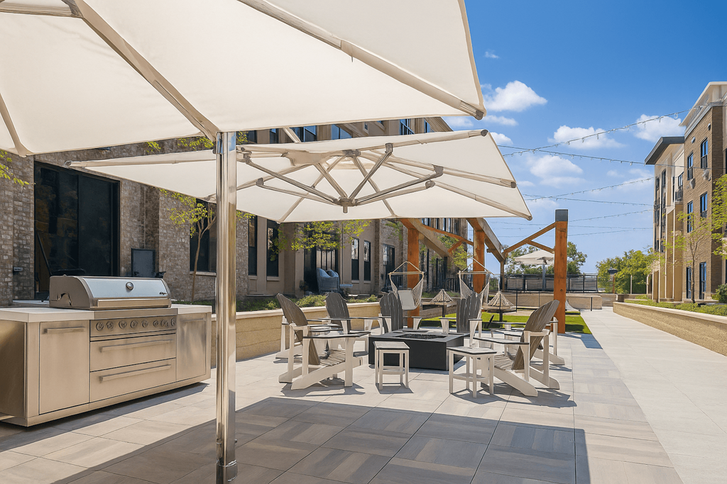 A patio with a grill and chairs under a white umbrella.