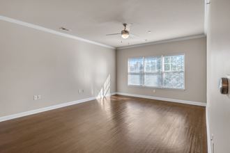 an empty living room with wood floors and a ceiling fan