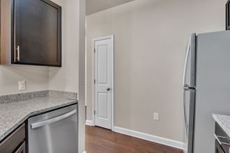 a kitchen with granite counter tops and a stainless steel refrigerator
