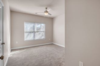 an empty living room with a ceiling fan and a window