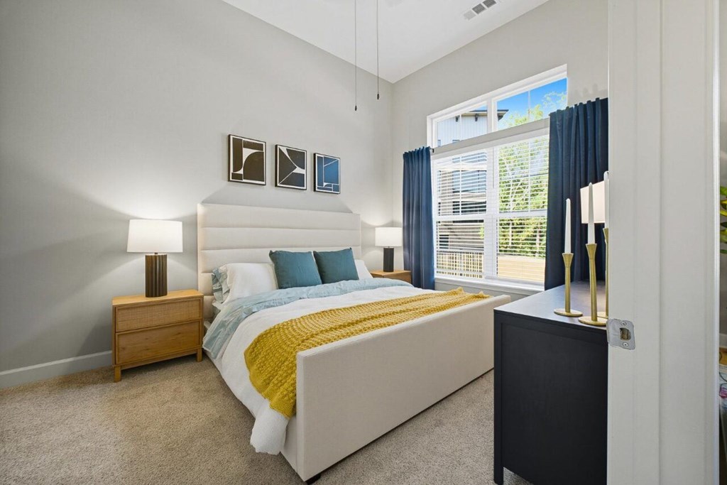 A bedroom with a bed, nightstand, and window.