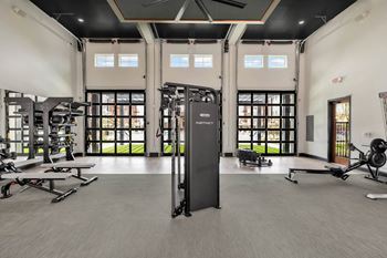 a large fitness room with exercise equipment and windows