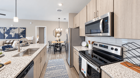 Model apartment kitchen with stainless steel appliances, light wood cabinetry and an island at Argento at Riverwatch Apartments in Augusta, GA.