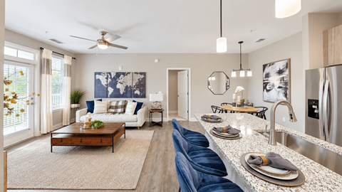 Open living and dining area beside a kitchen island in a model apartment at Argento at Riverwatch Apartments in Augusta, GA.