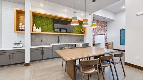 Clubhouse kitchen with a communal table, colorful pendant lights and a green accent wall at Argento at Sugarloaf.