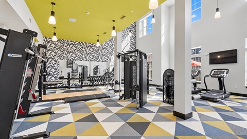 Fitness center with strength machines, free weights and treadmills beneath a yellow ceiling at Argento at Sugarloaf.