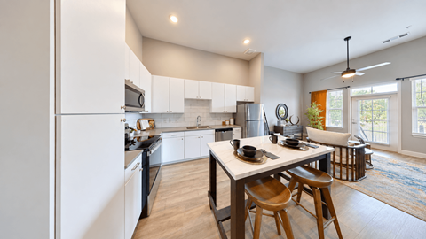 A2 one-bedroom apartment kitchen with white cabinets, stainless steel appliances, and a dining table at Argento at the Bridges in McDonough, GA.