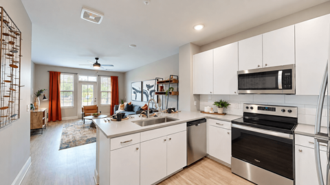 B3 apartment kitchen with white cabinets, stainless steel appliances, and a peninsula sink at Argento at the Bridges in McDonough, GA.