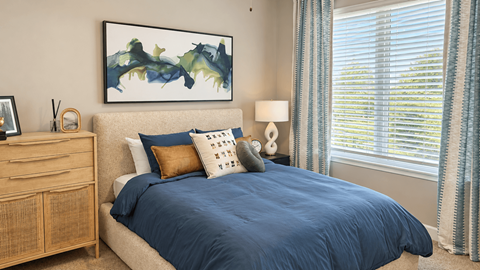 A bedroom with a bed, nightstand, and a painting on the wall.