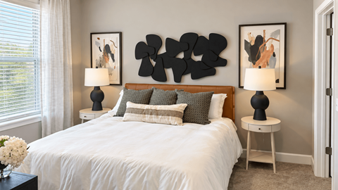 A bedroom with a white bed and two black lamps.