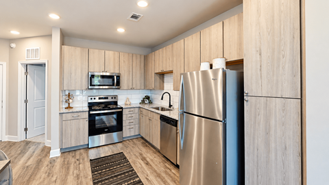 A kitchen with a refrigerator, oven, and microwave.