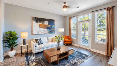 A living room with a white couch, a painting on the wall, and a ceiling fan.
