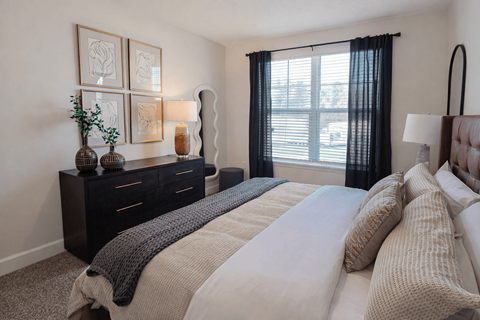 A bedroom with a large bed and a window with black curtains.