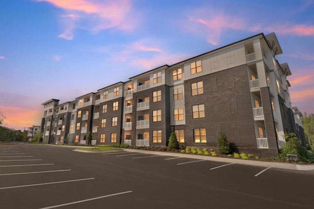 A large apartment building with a parking lot in front.