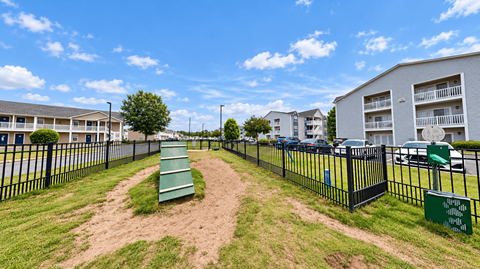 Fenced dog park with an agility ramp and pet waste station at Canterbury Apartments in Myrtle Beach, SC.