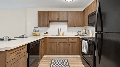 Kitchen with wood cabinets, black appliances and a breakfast bar at Canterbury Apartments in Myrtle Beach, SC.