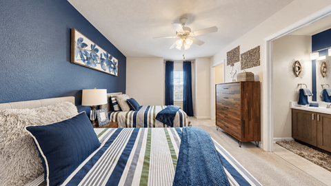 A bedroom with a bed, a dresser, and a ceiling fan.