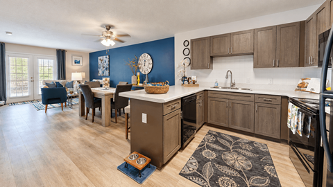 Kitchen with gray cabinets, black appliances and an adjoining furnished living area at Canterbury Apartments in Myrtle Beach, SC.