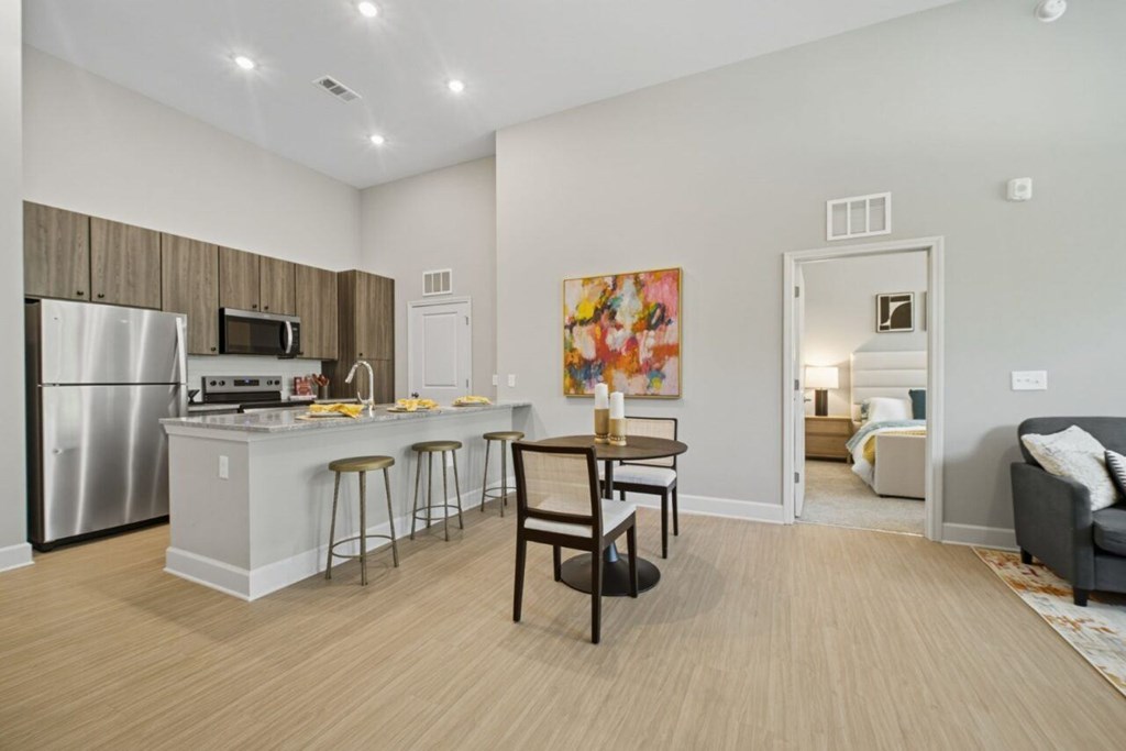 A kitchen with a refrigerator, microwave, and bar stools.
