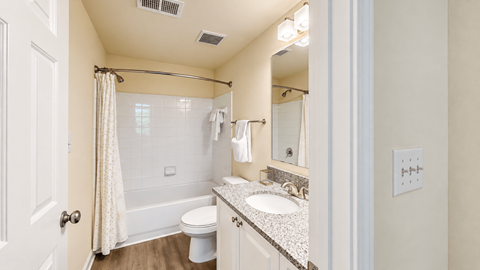 Bathroom with a white vanity, speckled countertop, and tiled tub and shower at Elevation 3505 in Atlanta, GA.