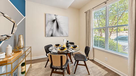 Dining area with a round glass table, four chairs, and a large window at Elevation 3505 in Atlanta, GA.