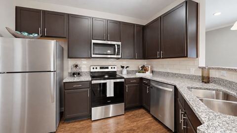 Apartment kitchen with dark cabinets and stainless steel appliances at Enclave at Bailes Ridge in Indian Land, SC.