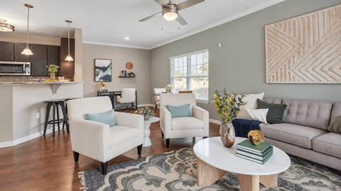 Living room with a sofa, two armchairs, and an open kitchen at Enclave at Bailes Ridge in Indian Land, SC.