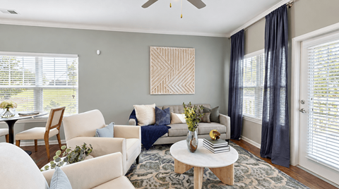 Furnished living room with large windows and balcony access at Enclave at Bailes Ridge in Indian Land, SC.