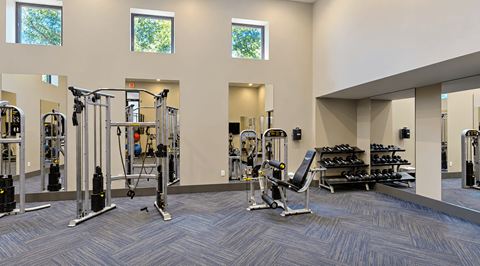 Fitness center with strength training machines, a weight bench and dumbbells at Icon Avondale Apartments in Decatur, GA.