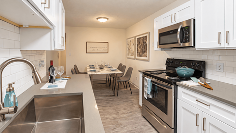 Kitchen with white cabinets, gray countertops and a subway tile backsplash overlooking the dining area at Icon Avondale Apartments in Decatur, GA.