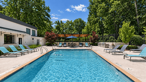 Swimming pool with lounge chairs beside the clubhouse at Icon Avondale Apartments in Decatur, GA.